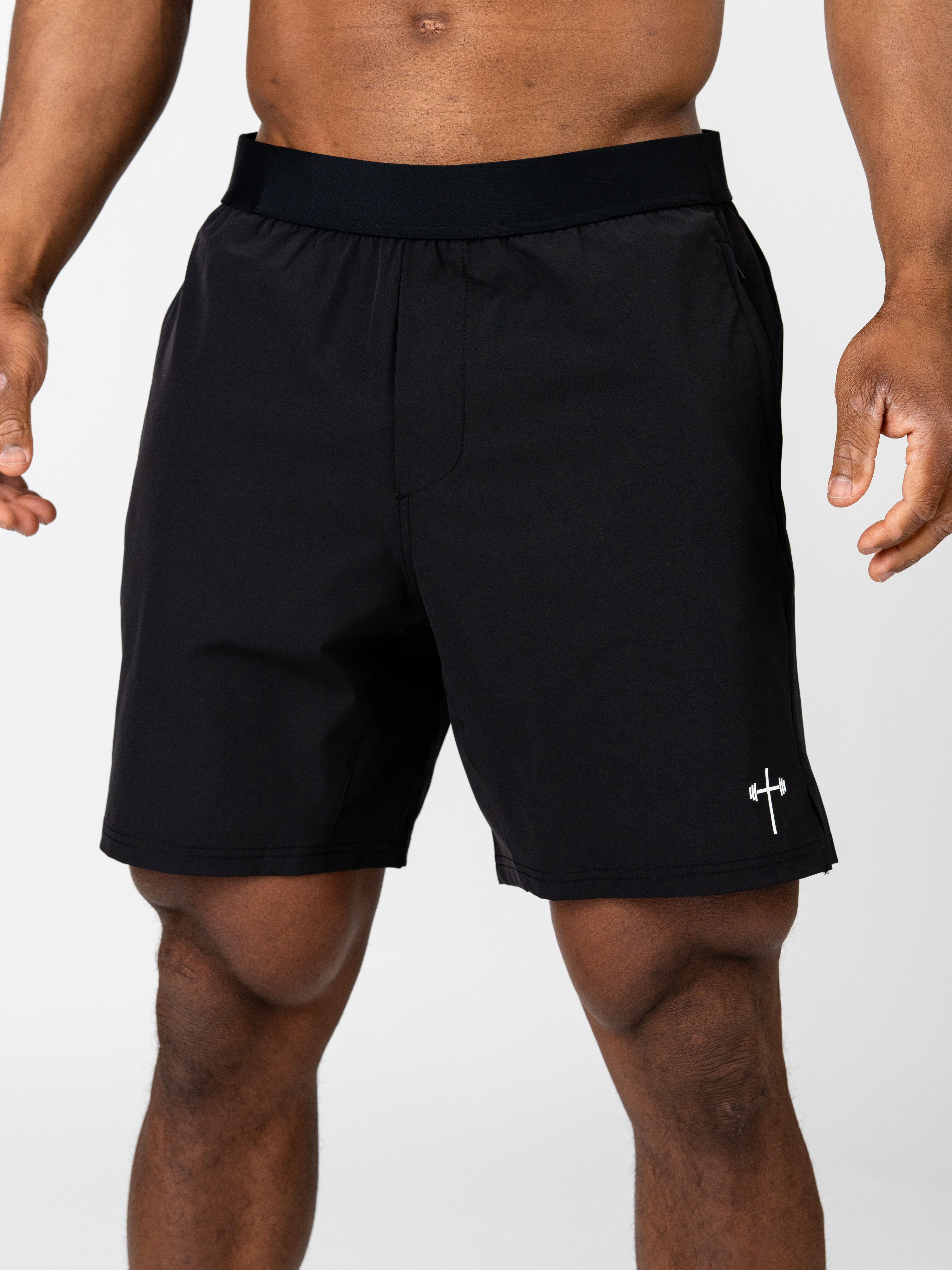 Man wearing black Essential Training Shorts with a small white cross and barbell logo on the left leg, designed for lightweight, breathable Christian fitness apparel.