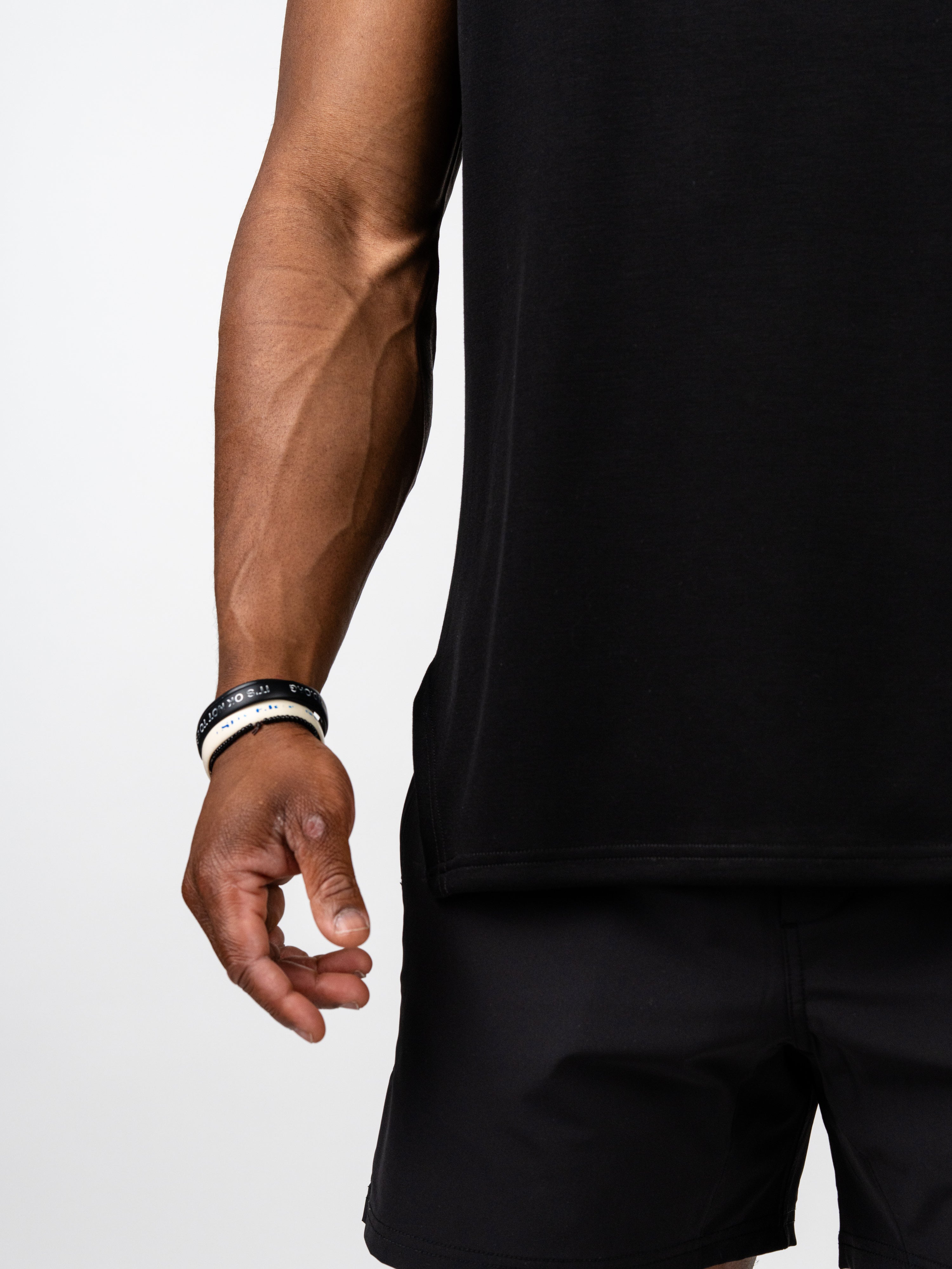 Close-up of a person wearing the Essential Sleeveless Hoodie in black, showcasing the breathable fabric and sleeveless design ideal for unrestricted arm movement during workouts.