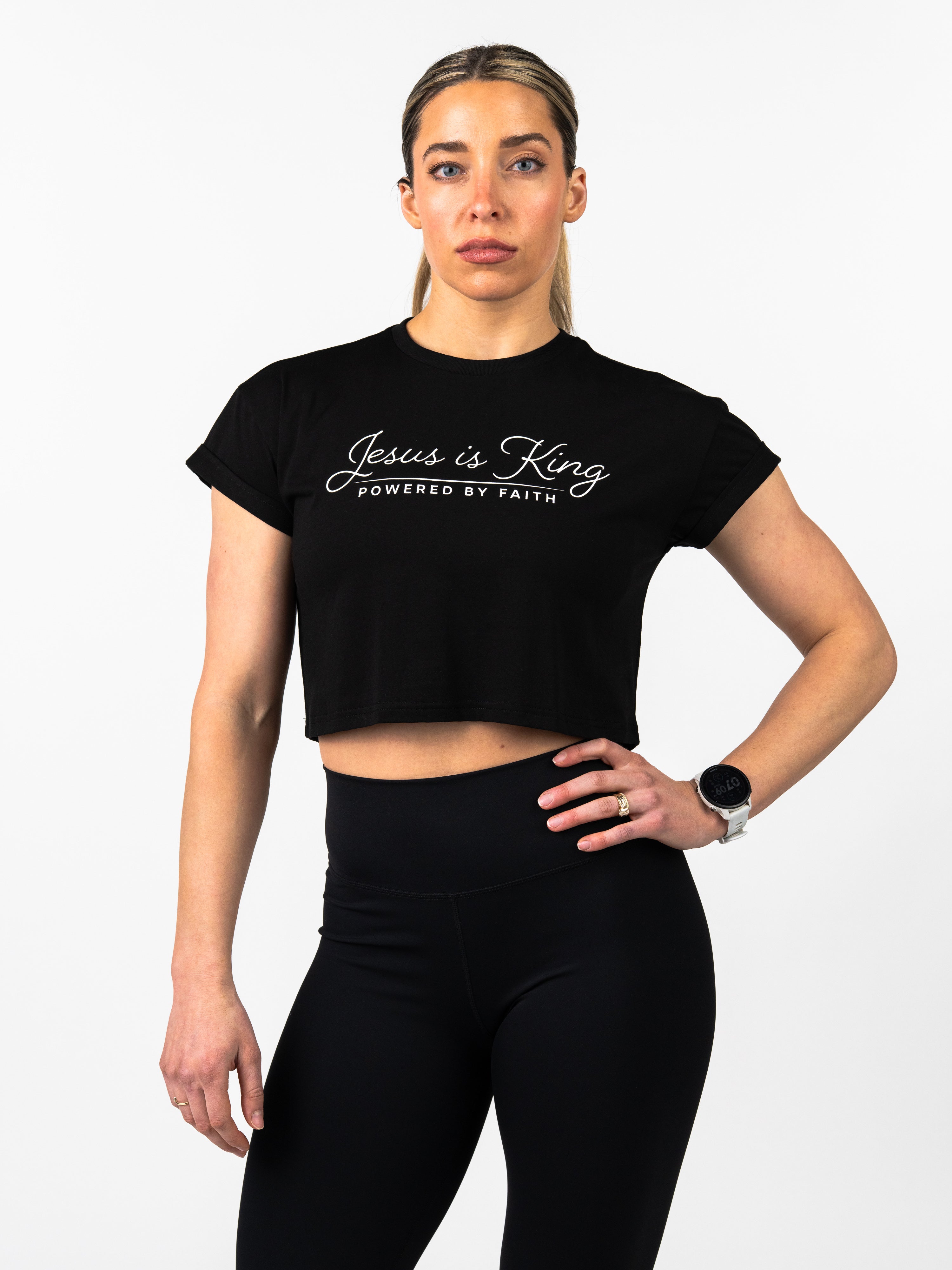 Woman wearing a black crop top with 'Jesus is King, Powered by Faith' text on a white background