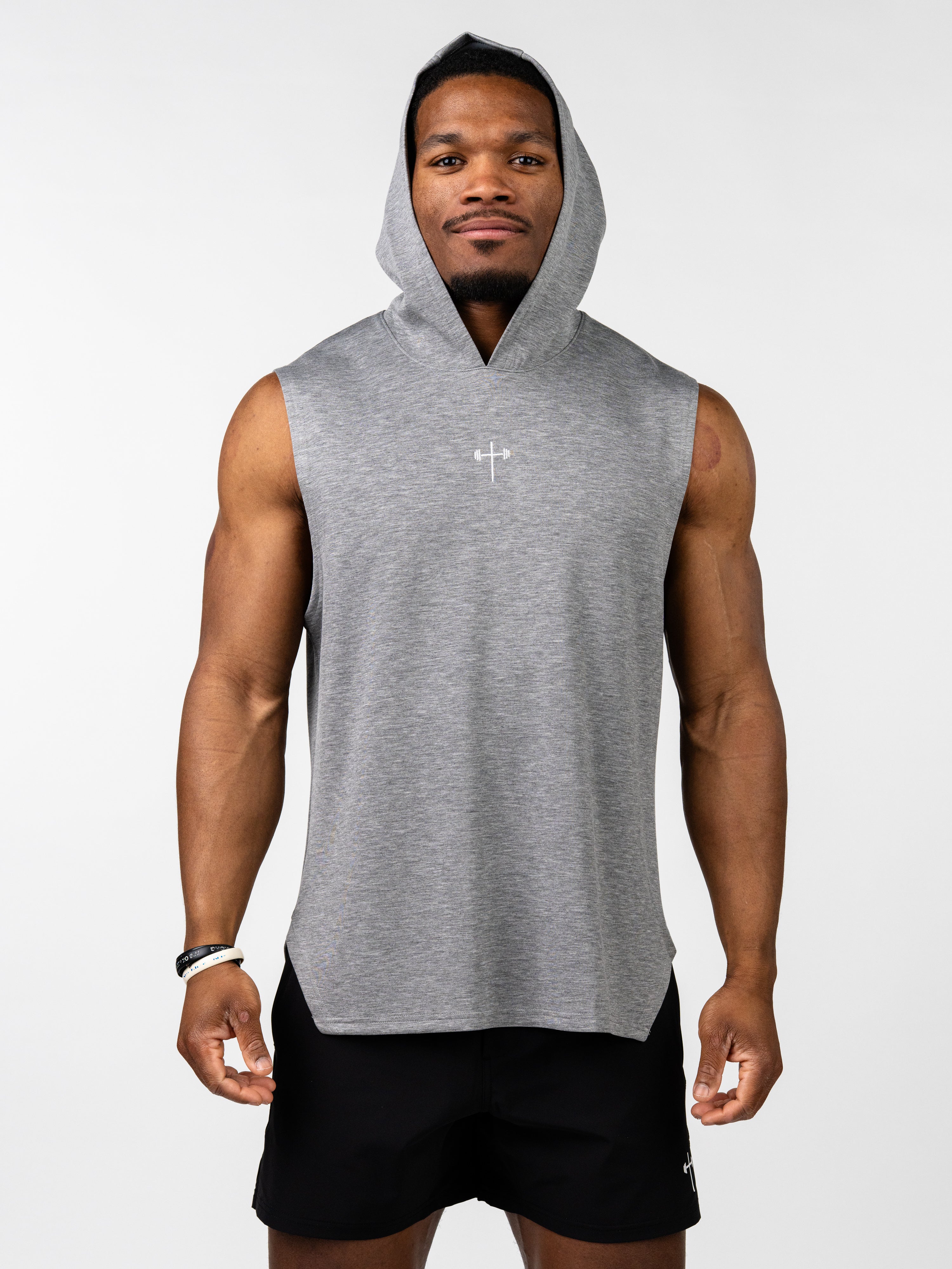 Athletic man wearing the Essential Sleeveless Hoodie in gray with a subtle Christian cross and barbell logo on the chest, styled for fitness and freedom of movement.