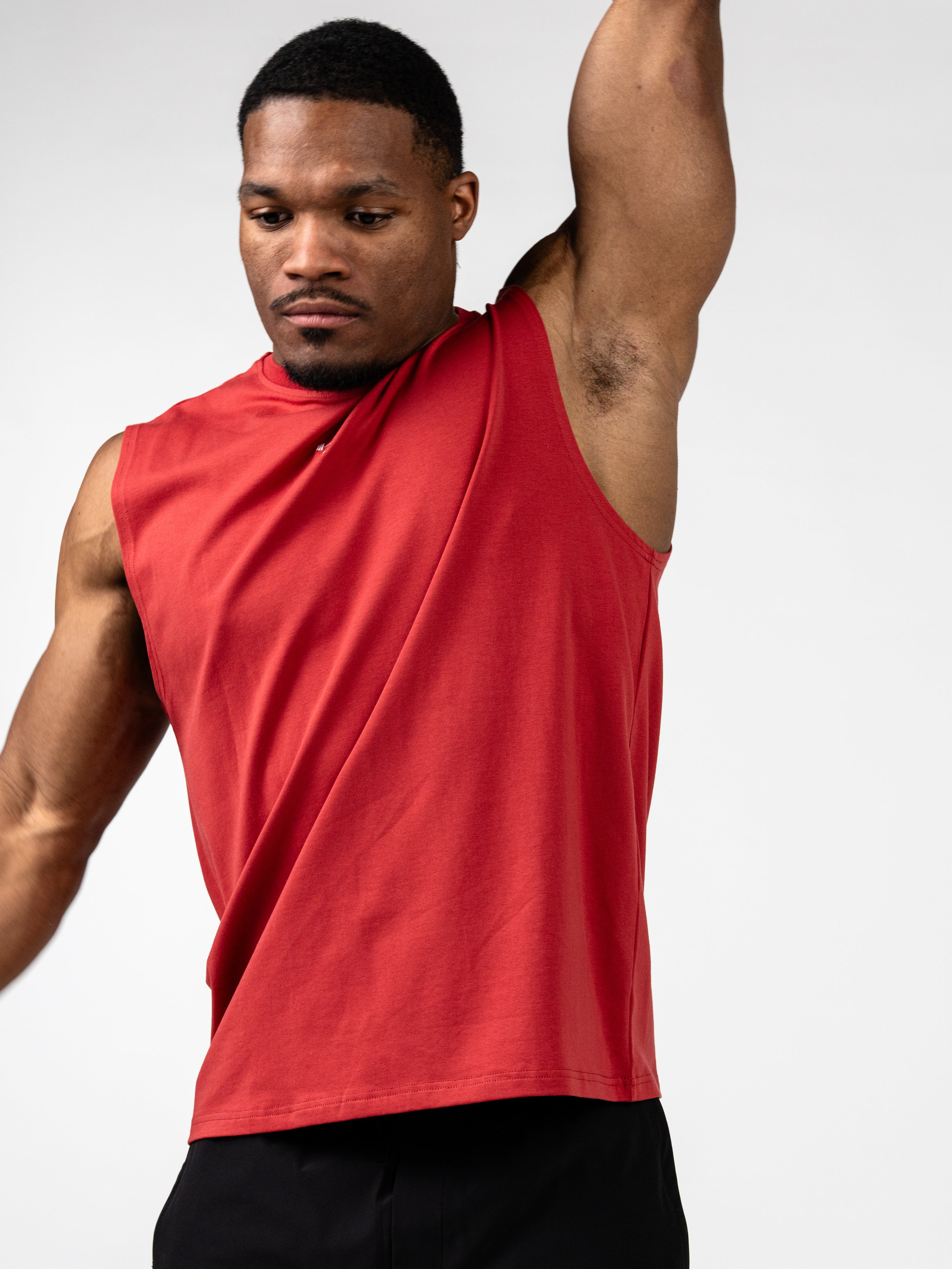 Man wearing red Vital Cross Sleeveless Tank raising one arm, demonstrating lightweight, breathable Christian fitness apparel designed for intense workouts and unrestricted movement.