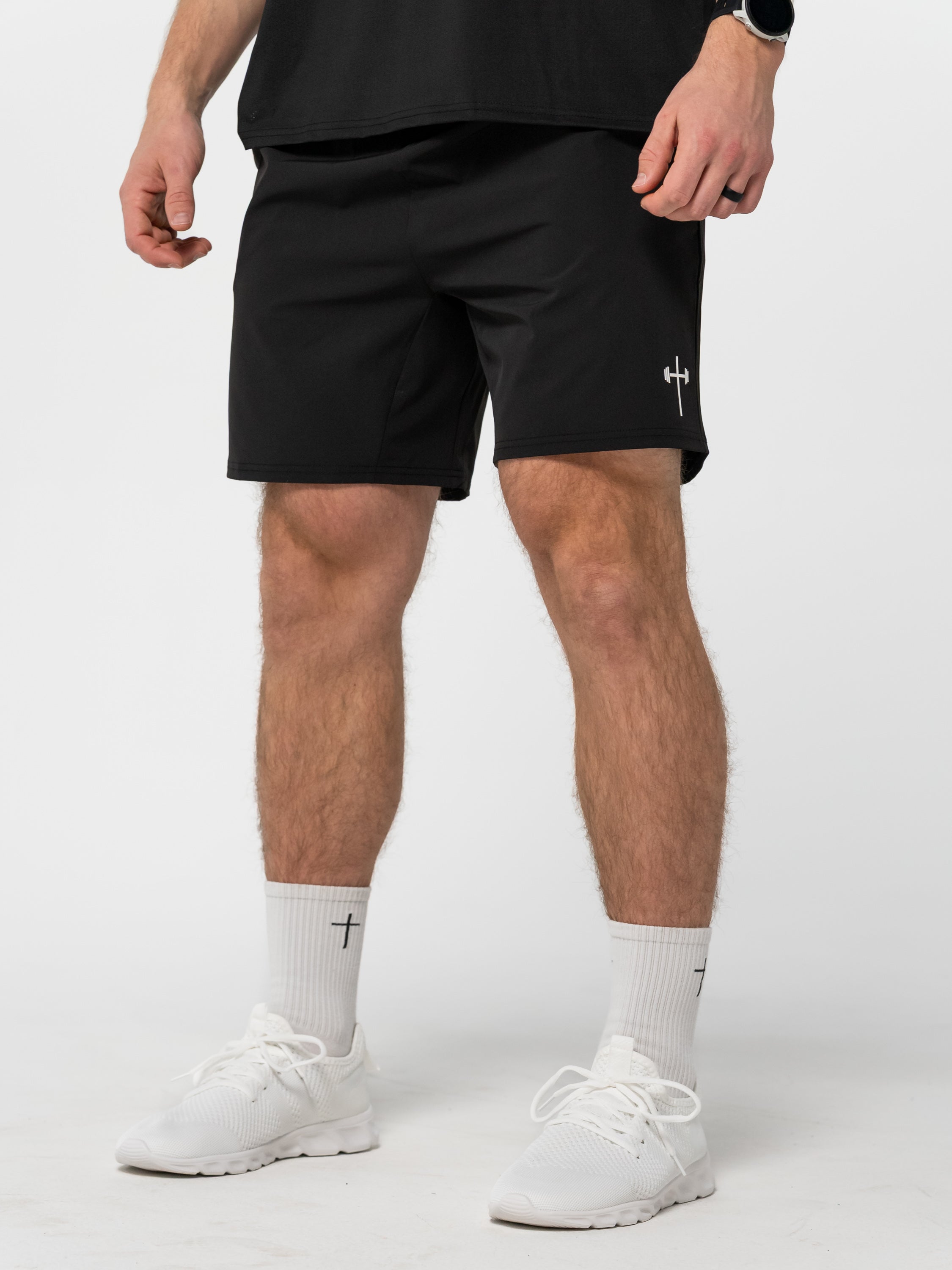 Person wearing black shorts and white socks with a logo on a white background