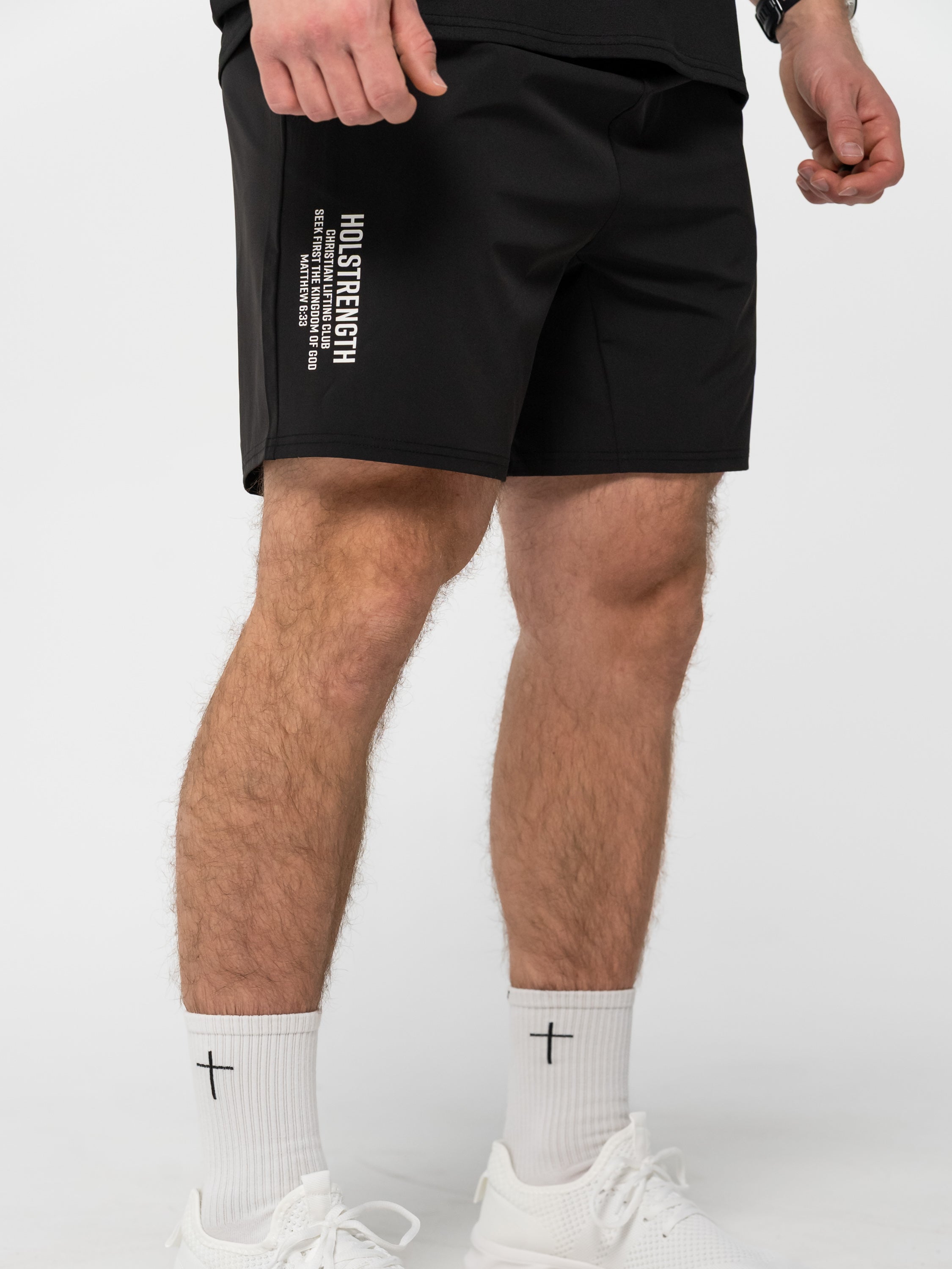 Person wearing black shorts with visible branding on a white background