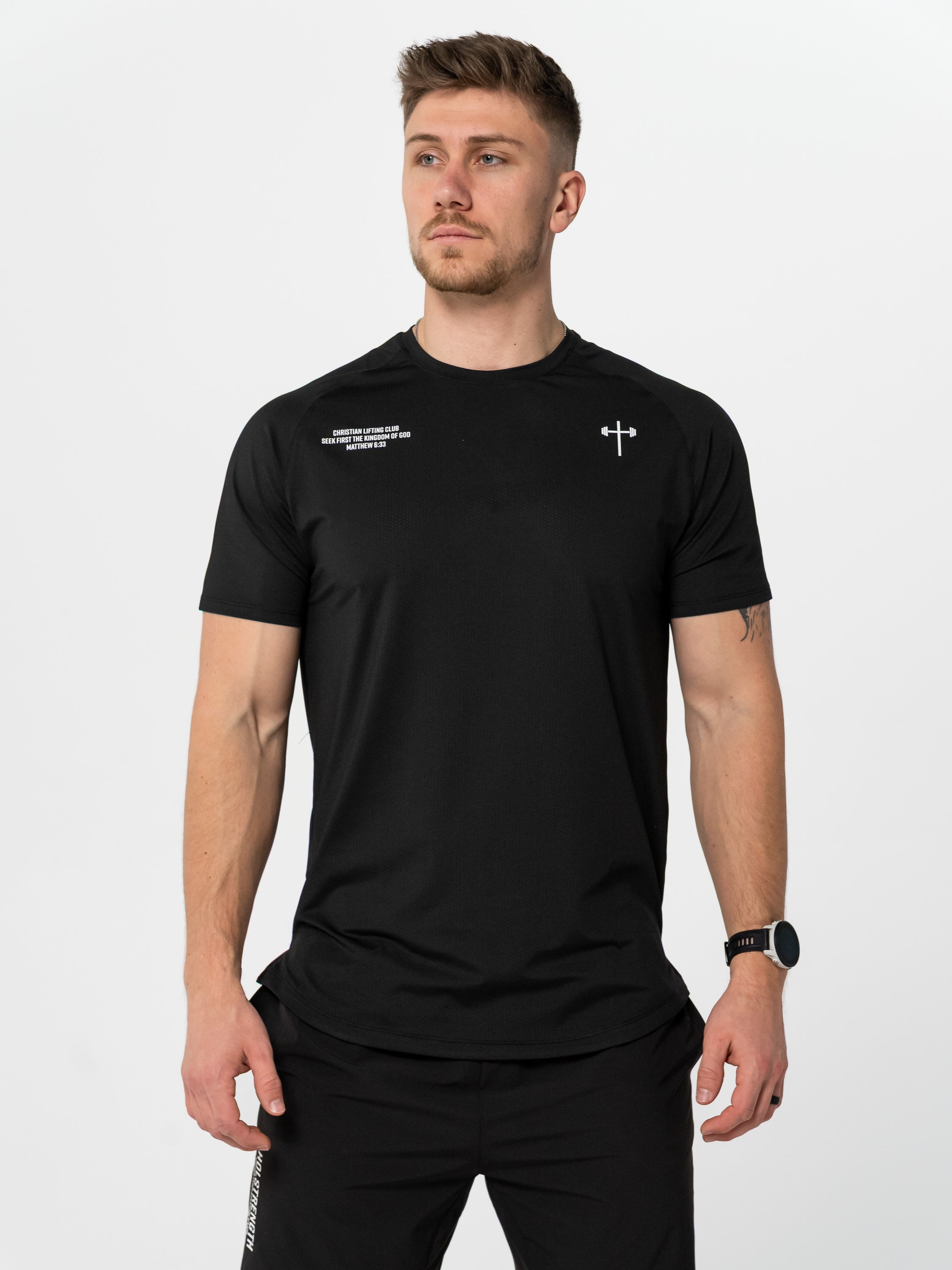 Man wearing a black t-shirt with a logo on a light gray background