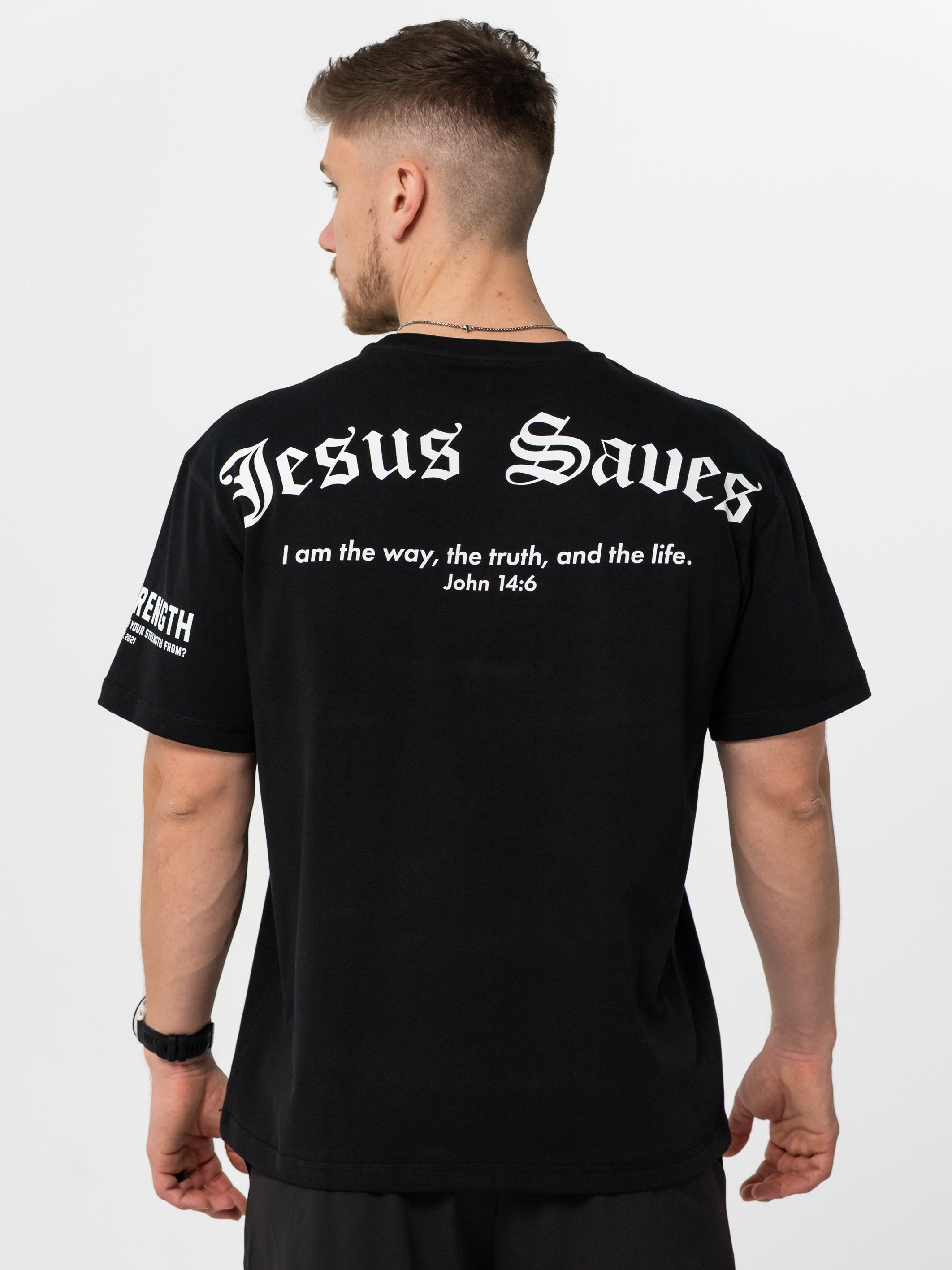 Man wearing a black t-shirt with 'Jesus Saves' text on the back, standing against a white background.