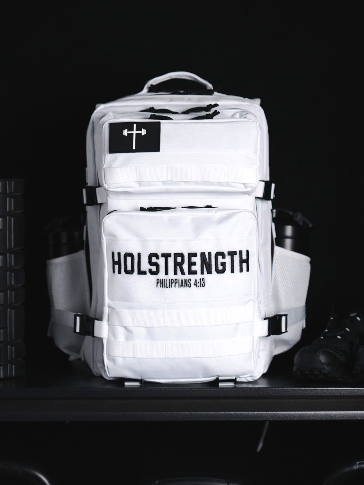 HolStrength 45L Tactical Backpack in white with multiple compartments front webbing cross logo and padded shoulder straps displayed against a dark background