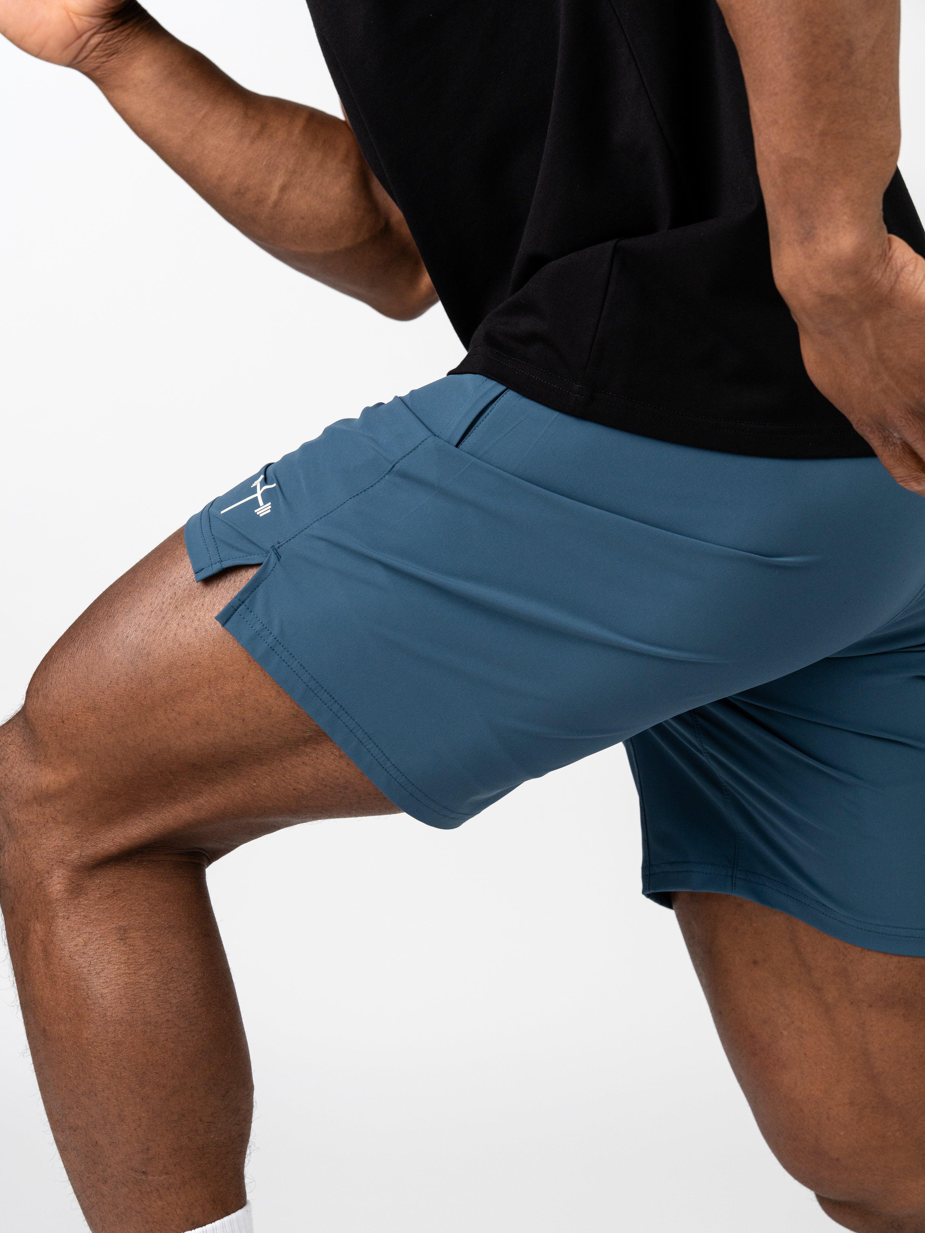 Close-up of a person wearing blue Essential Training Shorts in a dynamic workout pose, showcasing lightweight, breathable fabric ideal for Christian fitness apparel.