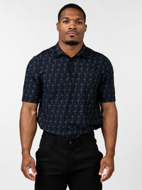 Man wearing a black Cross Premium Polo shirt patterned with subtle gray crosses, paired with black pants, standing against a plain white background.