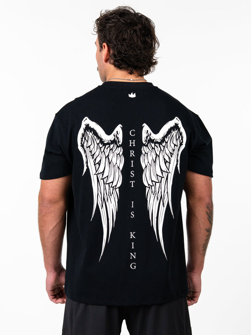 Person wearing a black t-shirt with angel wings and 'Christ is King' text on the back.