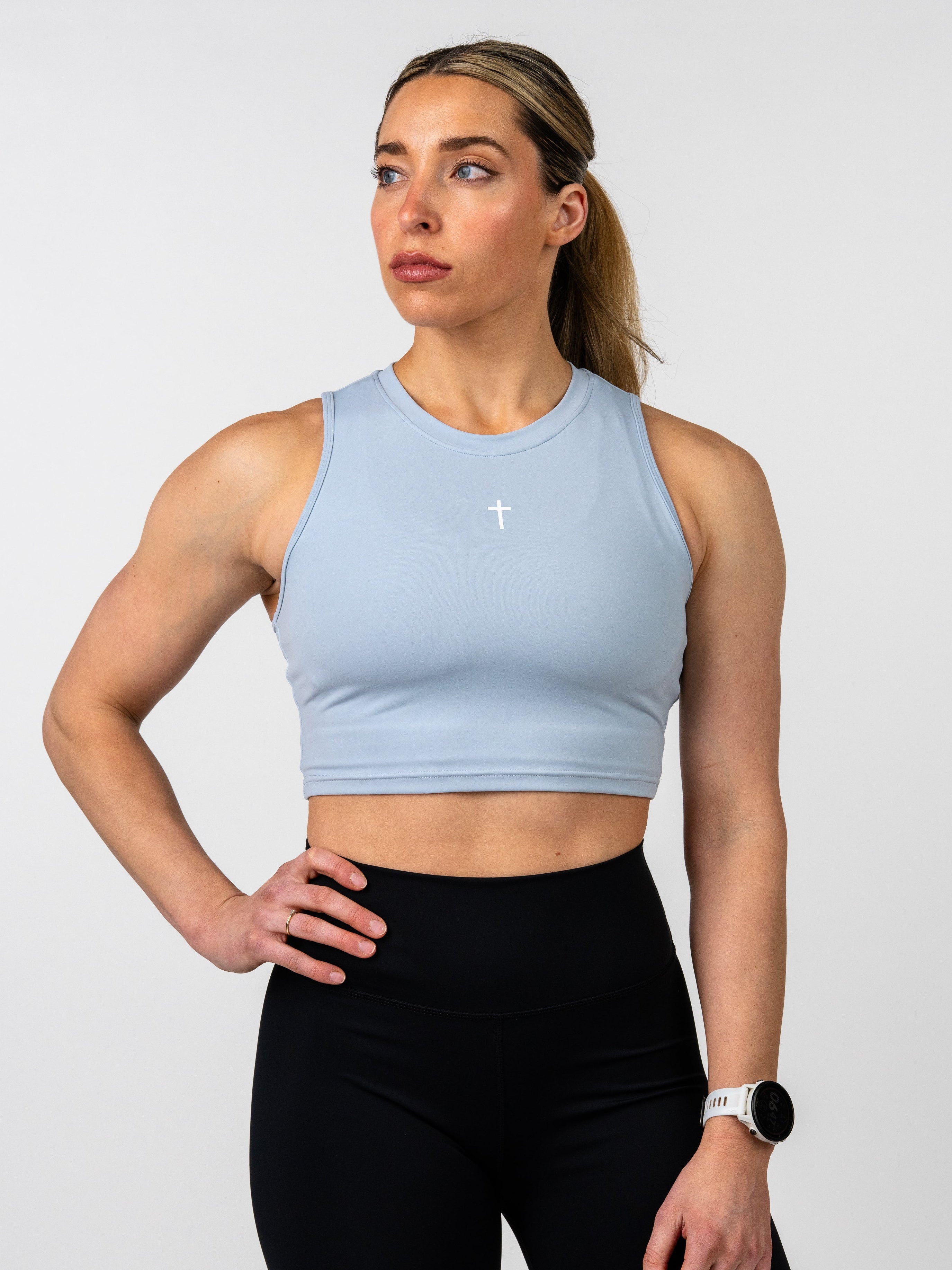 Woman wearing a light blue sports bra and black leggings on a white background