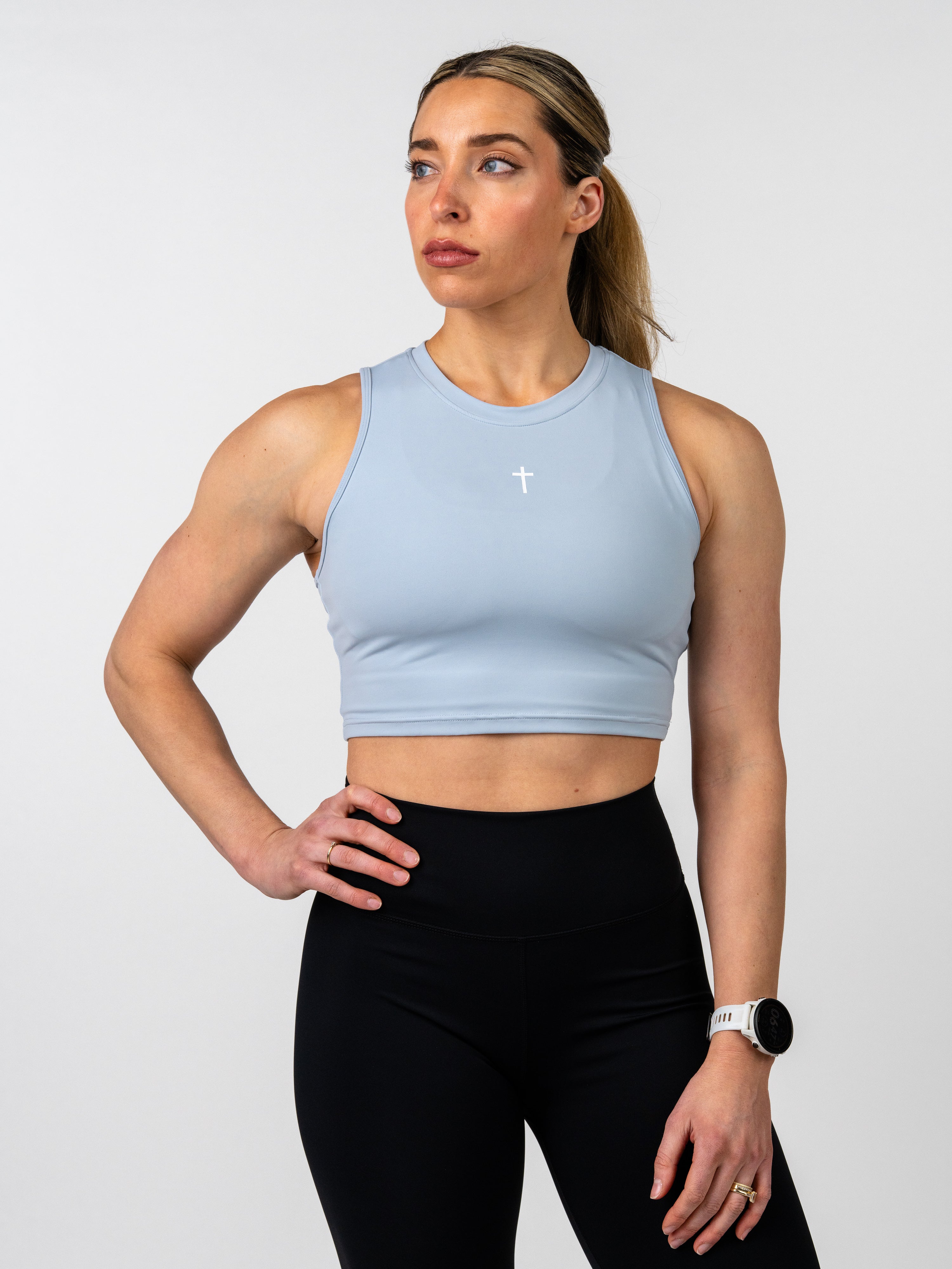 Woman wearing a light blue sports bra and black leggings on a white background