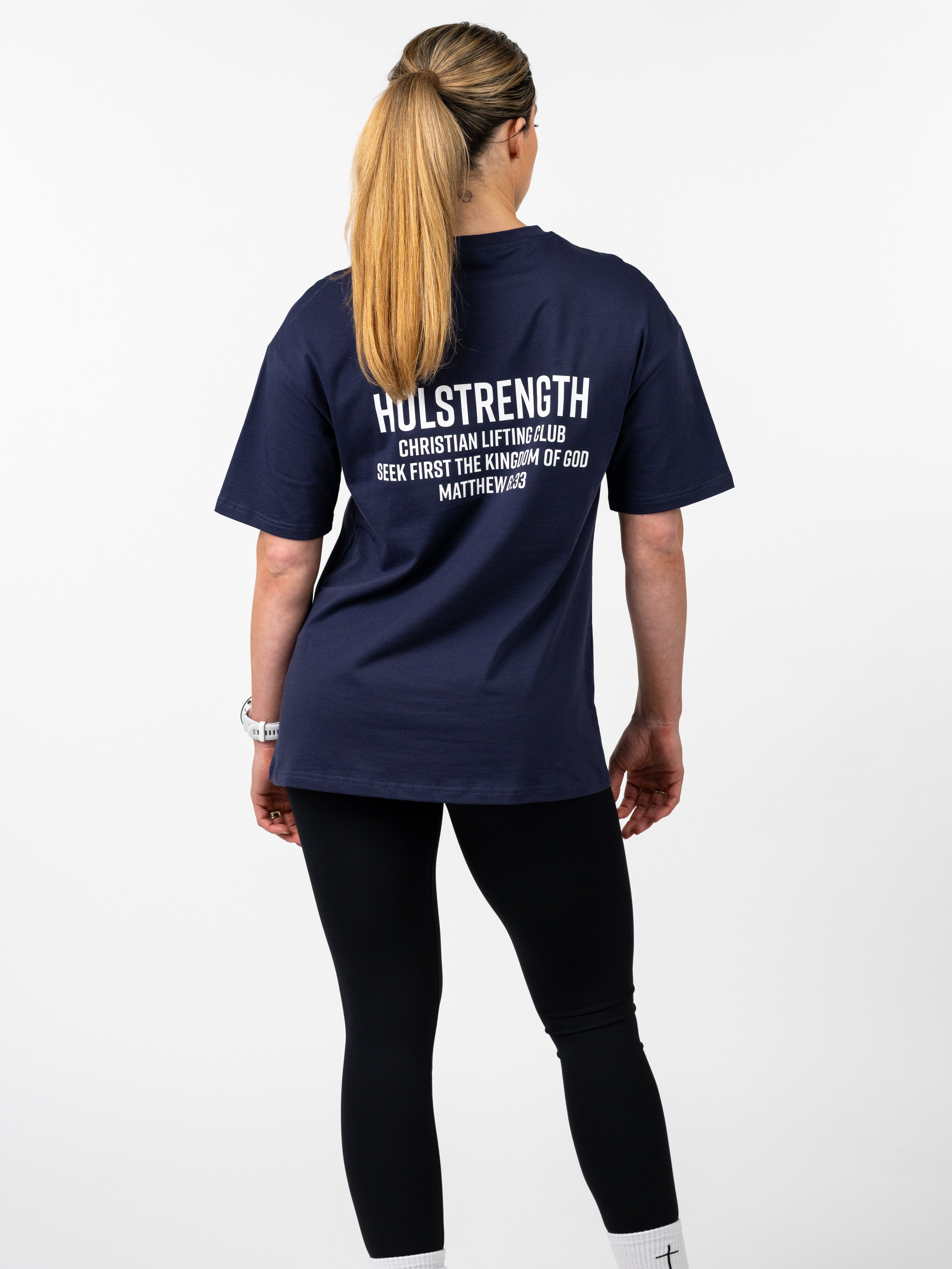 Person wearing a navy blue t-shirt with text on the back, standing against a white background