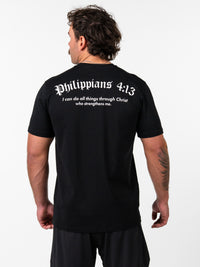 Man wearing a black Kingdom Performance Tee featuring the scripture Philippians 4:13 on the back, standing with his back to the camera against a plain white background.