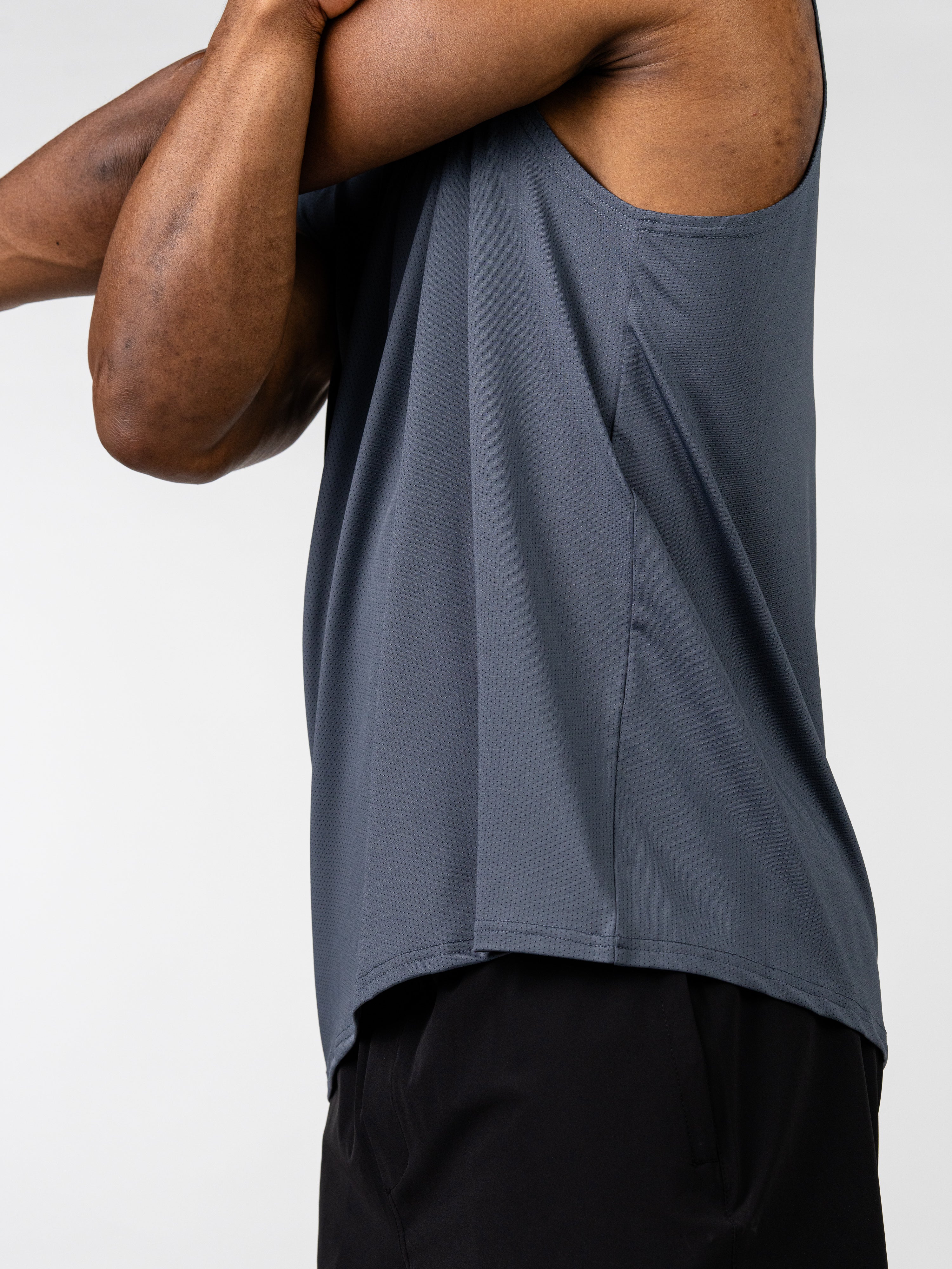 Side view of a person wearing a gray Carry Your Cross Premium Oversized Tank, designed for Christian fitness apparel with breathable, lightweight fabric suited for workouts and daily wear.