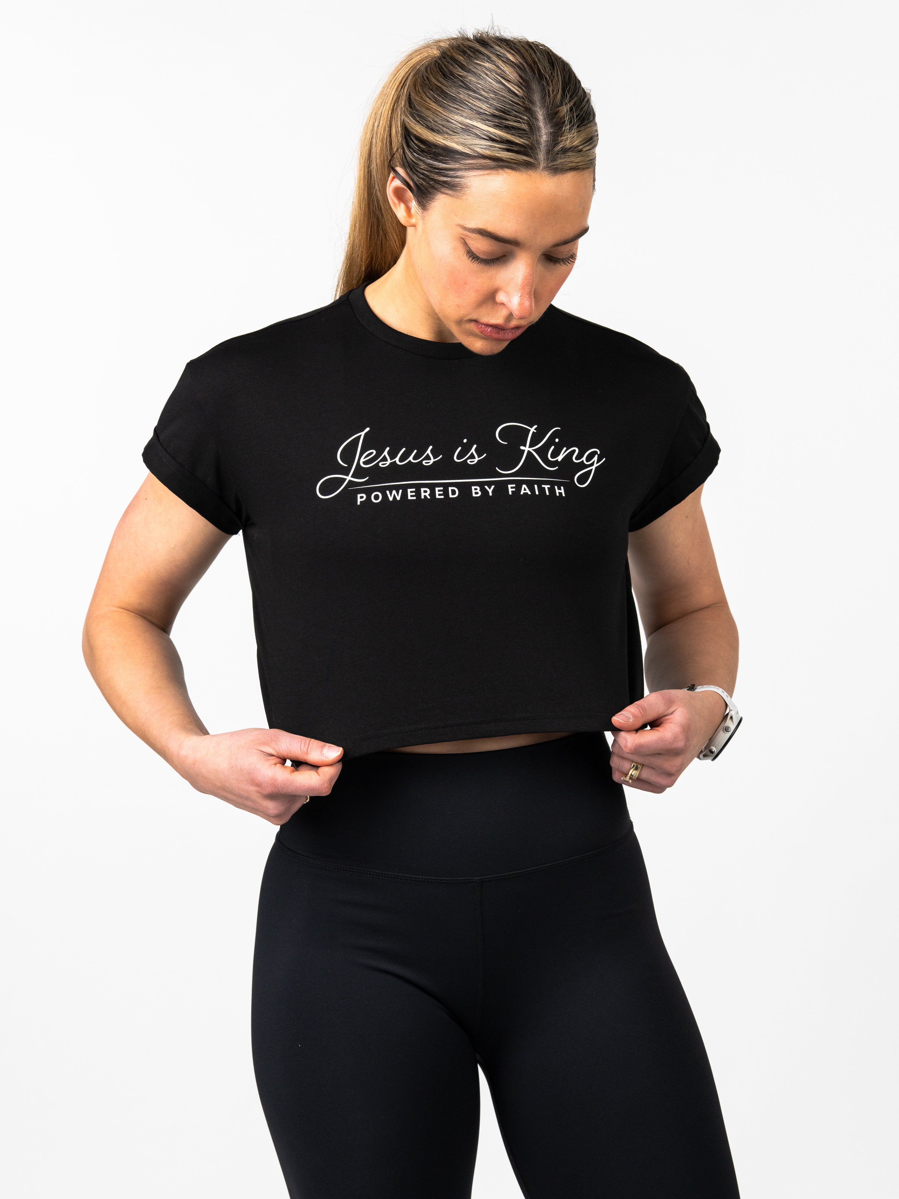 Woman wearing a black t-shirt with 'Jesus is King Powered by Faith' text on a white background