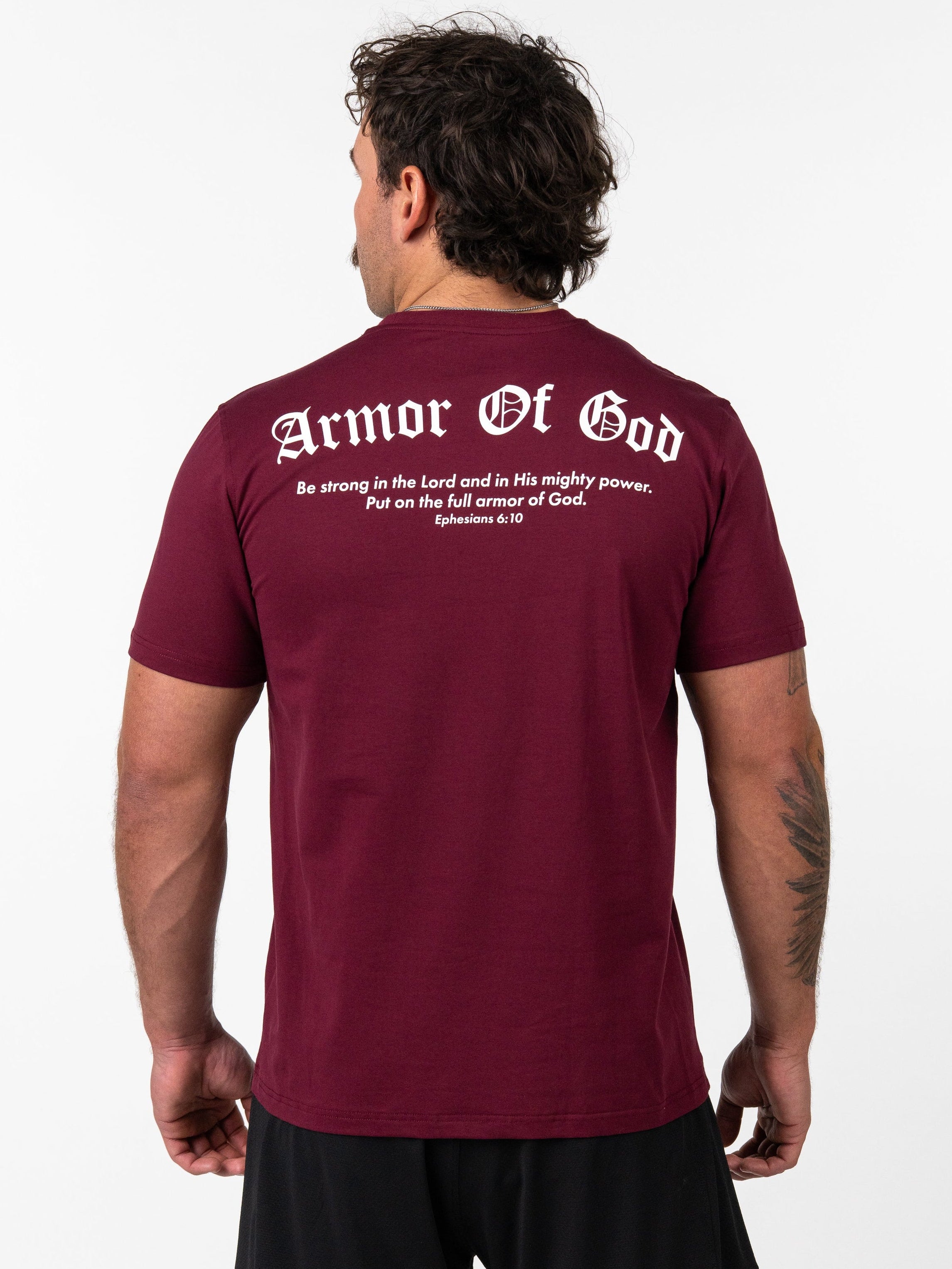Man wearing a maroon Kingdom Performance Tee showing the back with white text reading "Armor Of God" and a Bible verse from Ephesians 6:10, Christian fitness apparel.