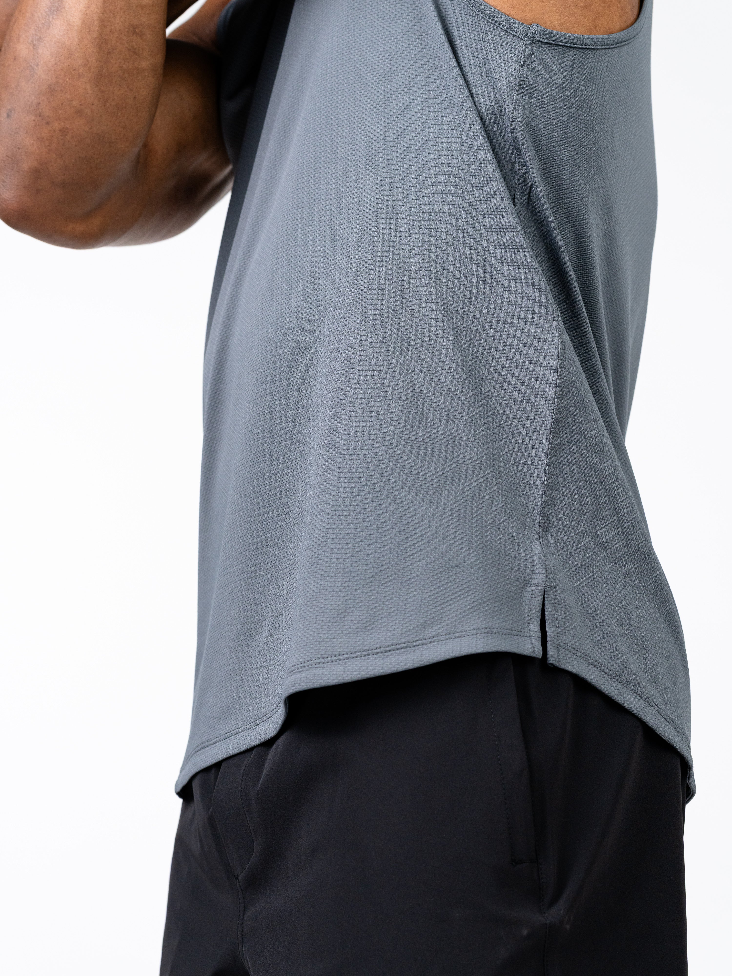 Close-up of a person wearing a gray Signature Tank made from breathable, sweat-wicking performance fabric designed for intense training and active movement.