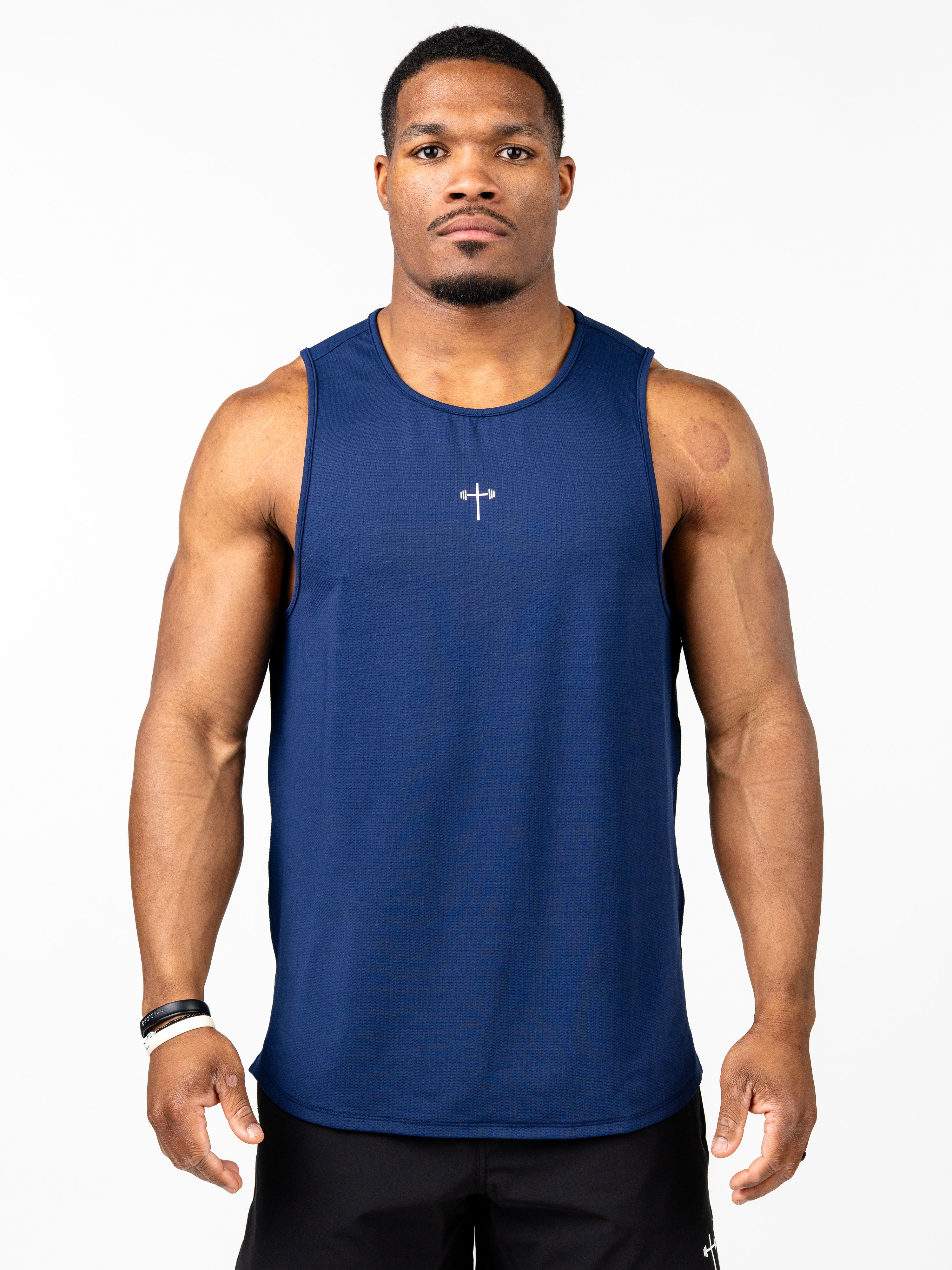 Man wearing a navy blue Signature Tank with a small white cross and barbell design on the chest, showcasing Christian gym clothing made for performance and intense training.