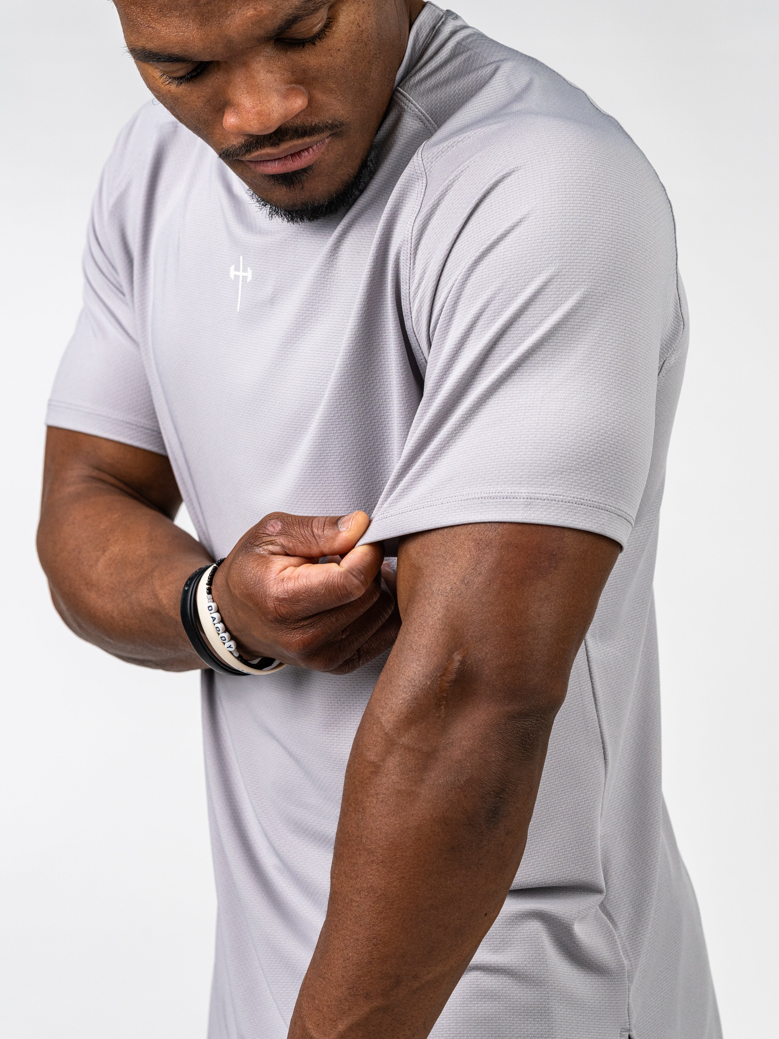 Athletic man wearing a light grey Signature Tee made from breathable, sweat-wicking performance fabric, showcasing 4-way stretch designed for intense training and durability.