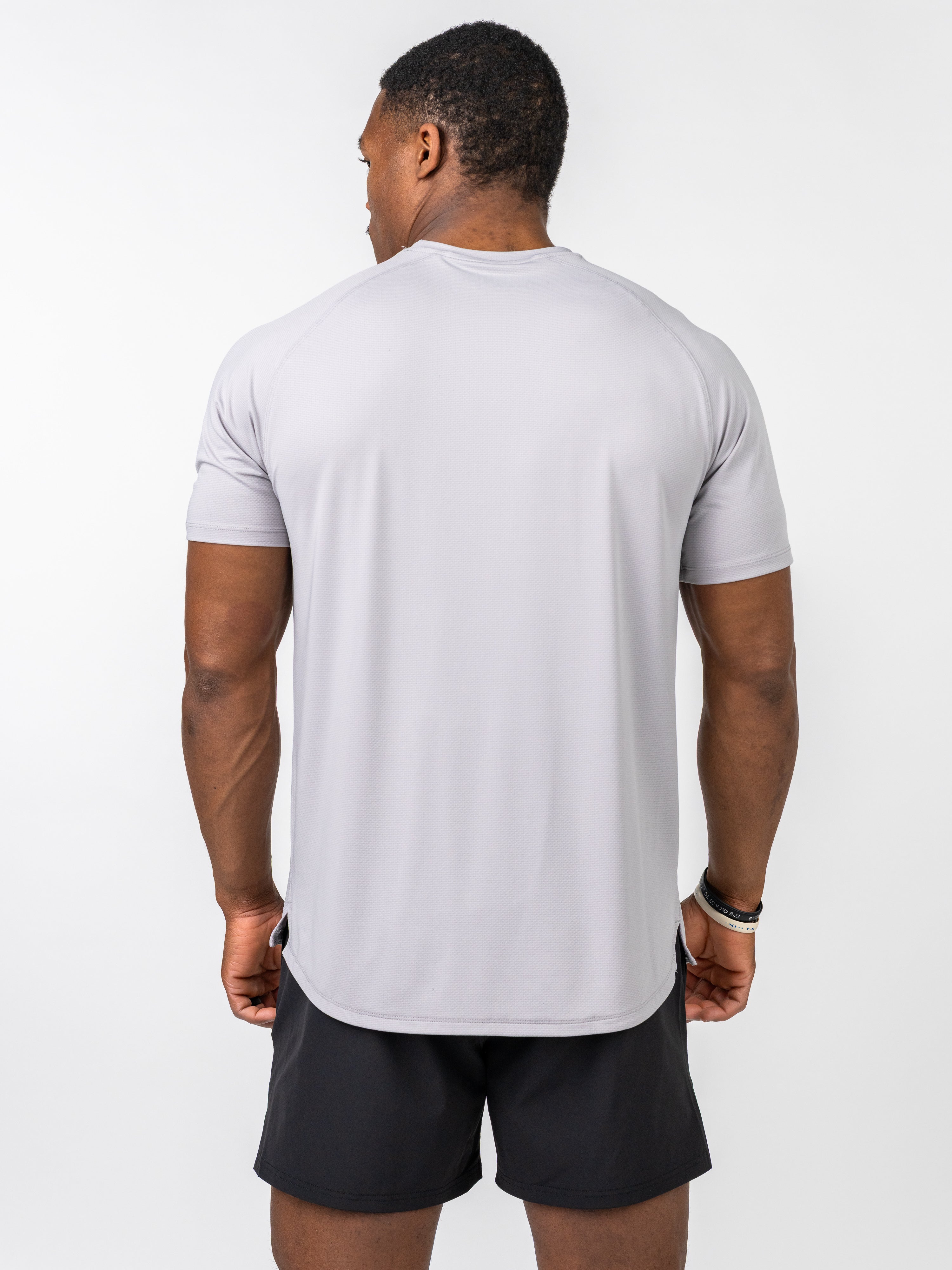 Man wearing light grey Signature Tee from the back, showing breathable, stretch performance fabric designed for intense training and durability.