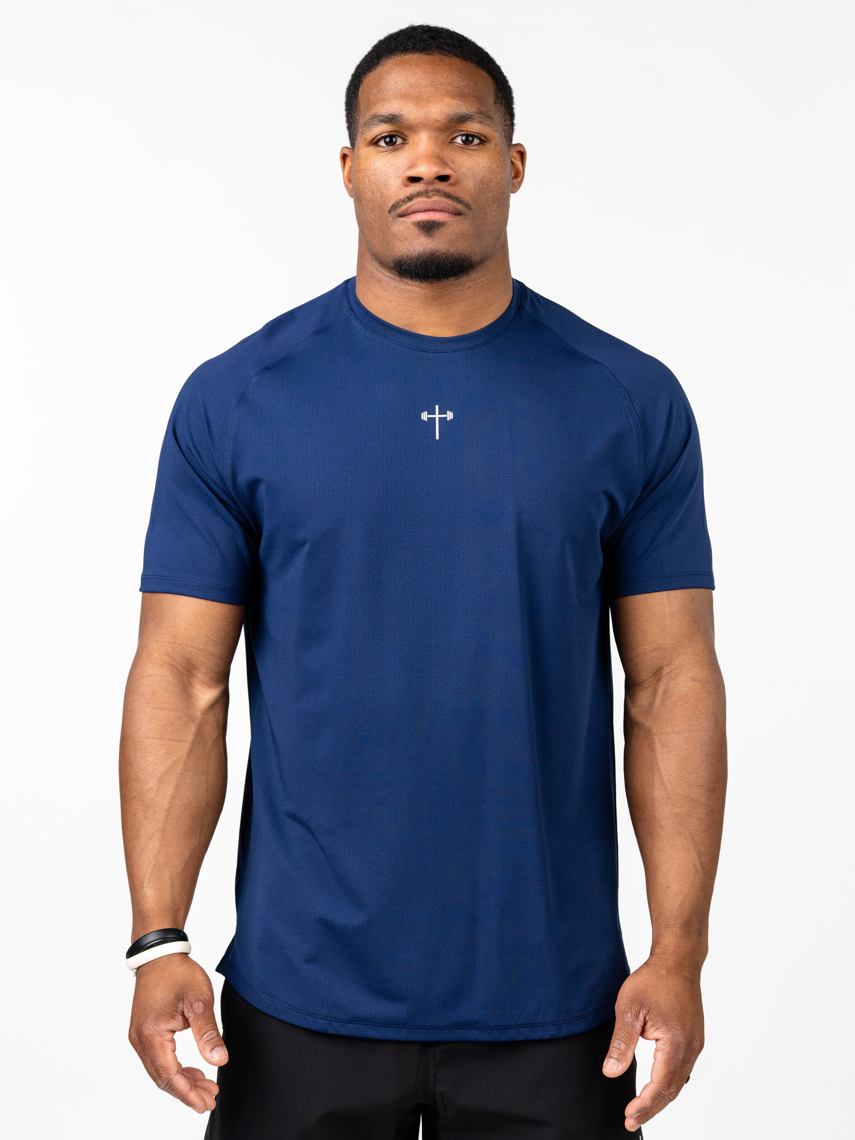 Athletic man wearing a navy blue Signature Tee featuring a small white Christian cross with barbell design on the chest, designed for Christian fitness apparel and performance.