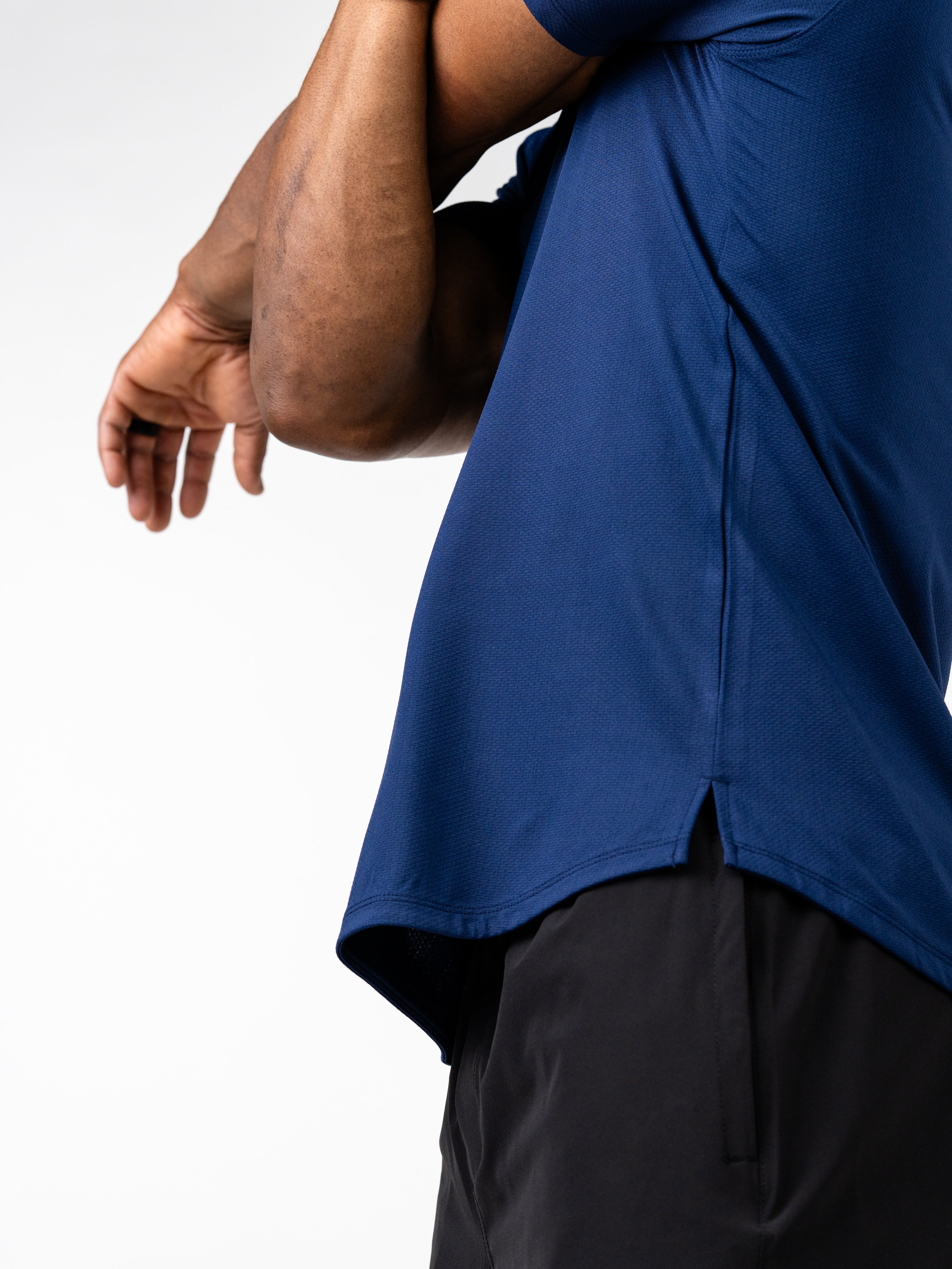 Close-up of a person wearing a navy blue Signature Tee made from breathable, sweat-wicking fabric with 4-way stretch, showcasing a comfortable fit for intense training and movement.