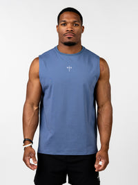 A muscular man wearing a blue Vital Cross Sleeveless Tank featuring a small white Christian cross with a barbell design on the chest, styled as Christian gym clothing for high-intensity workouts.