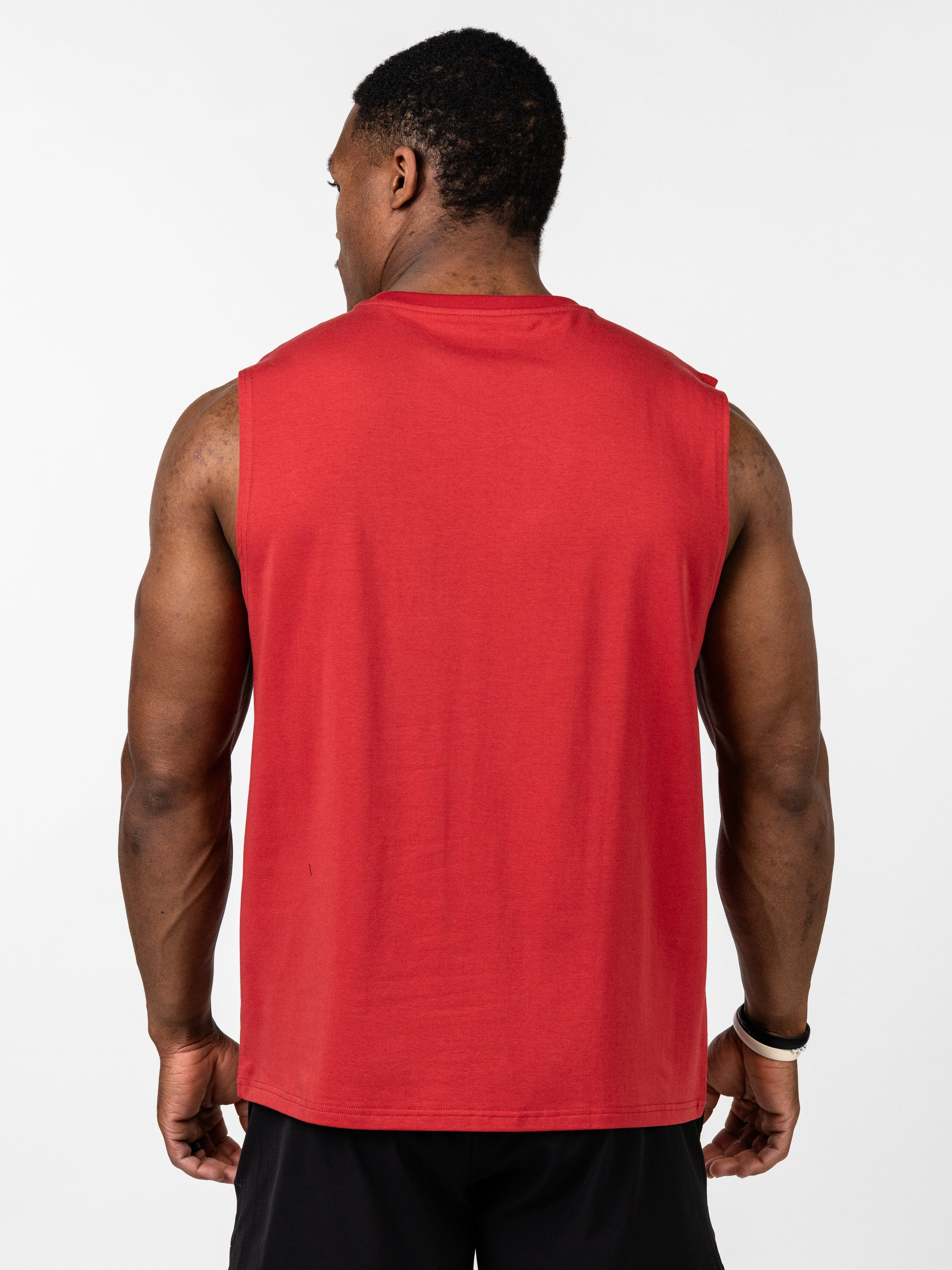 Male model seen from behind wearing a red Vital Cross Sleeveless Tank paired with black shorts, designed for comfort and freedom during high-output workouts.