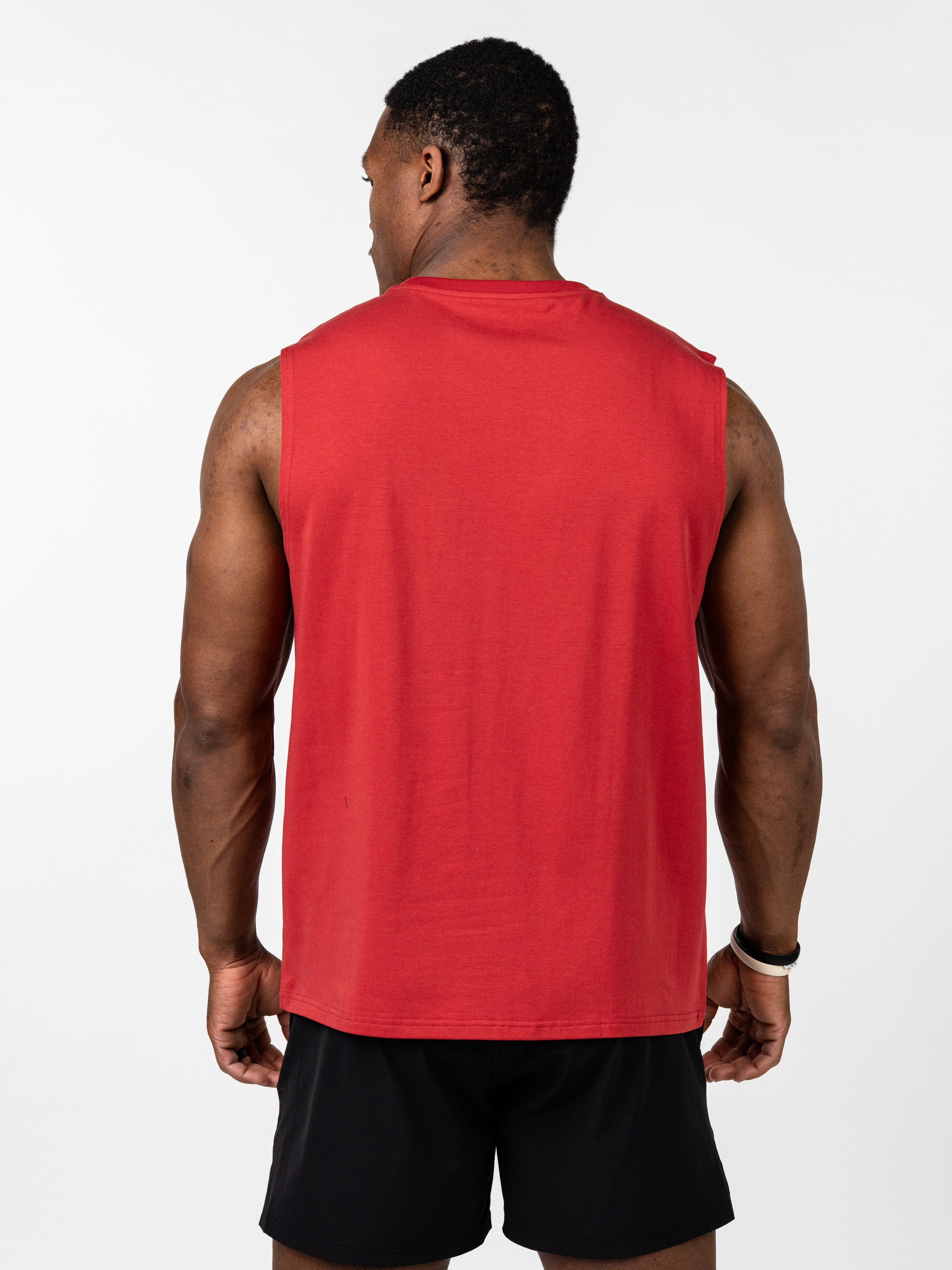 Male model seen from behind wearing a red Vital Cross Sleeveless Tank paired with black shorts, designed for comfort and freedom during high-output workouts.