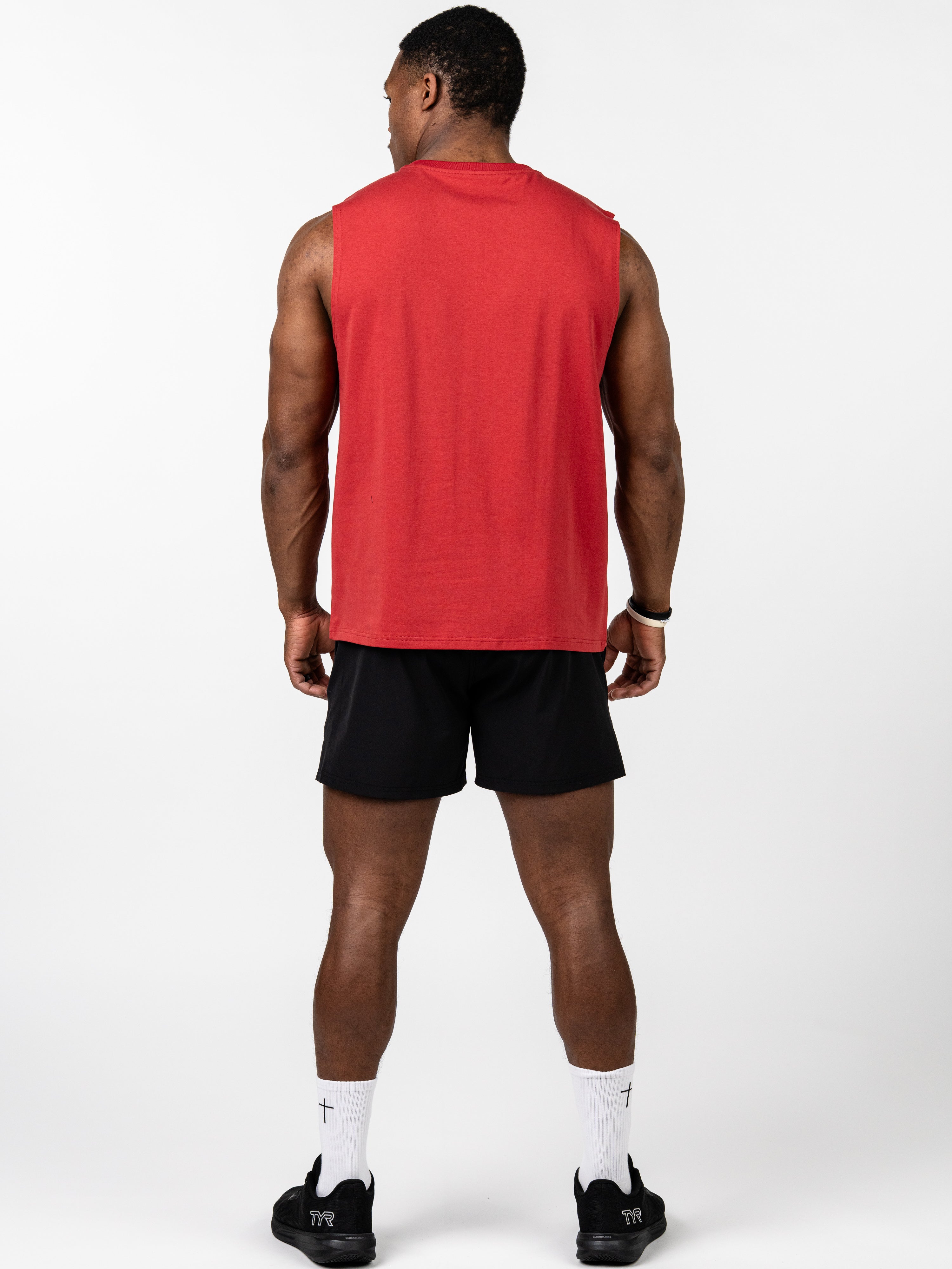 Athletic man wearing a red Vital Cross Sleeveless Tank with black shorts and white socks featuring a subtle cross design, shown from the back for a clear view of the tank.