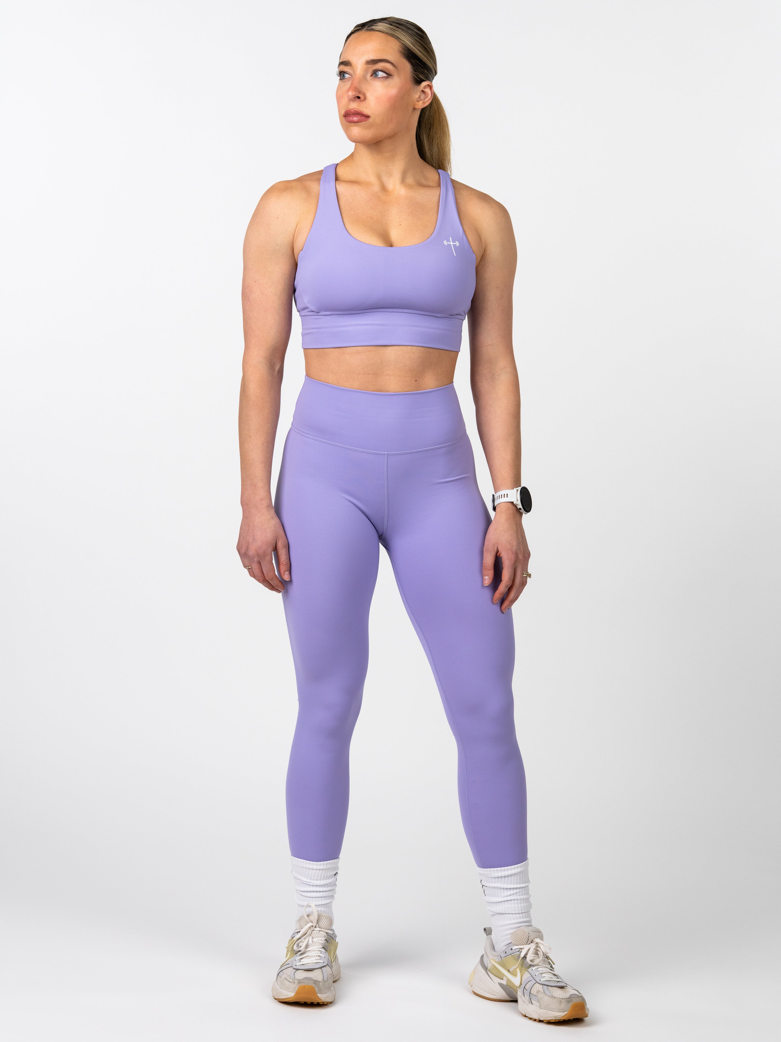 Woman wearing lavender Essential Sports Bra with matching high-waisted leggings, standing confidently for fitness workout in Christian activewear by HolStrength.