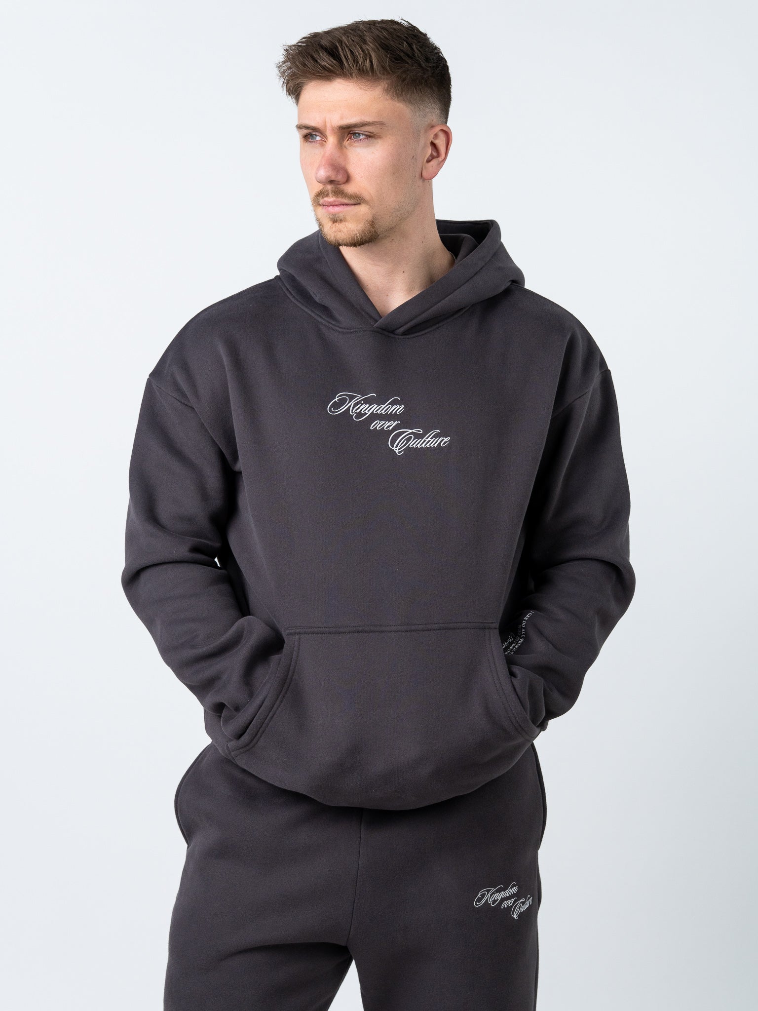 Man wearing a dark gray hoodie with branding on a light gray background