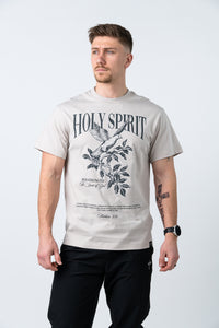 Man wearing a light beige t-shirt with a black graphic design of a dove and branches, featuring the text "HOLY SPIRIT" and scripture reference, paired with black pants.