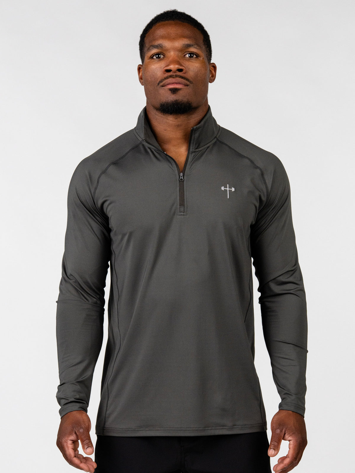A man wearing a dark gray long-sleeve athletic quarter-zip pullover with a small white chest logo, photographed against a light gray studio background.