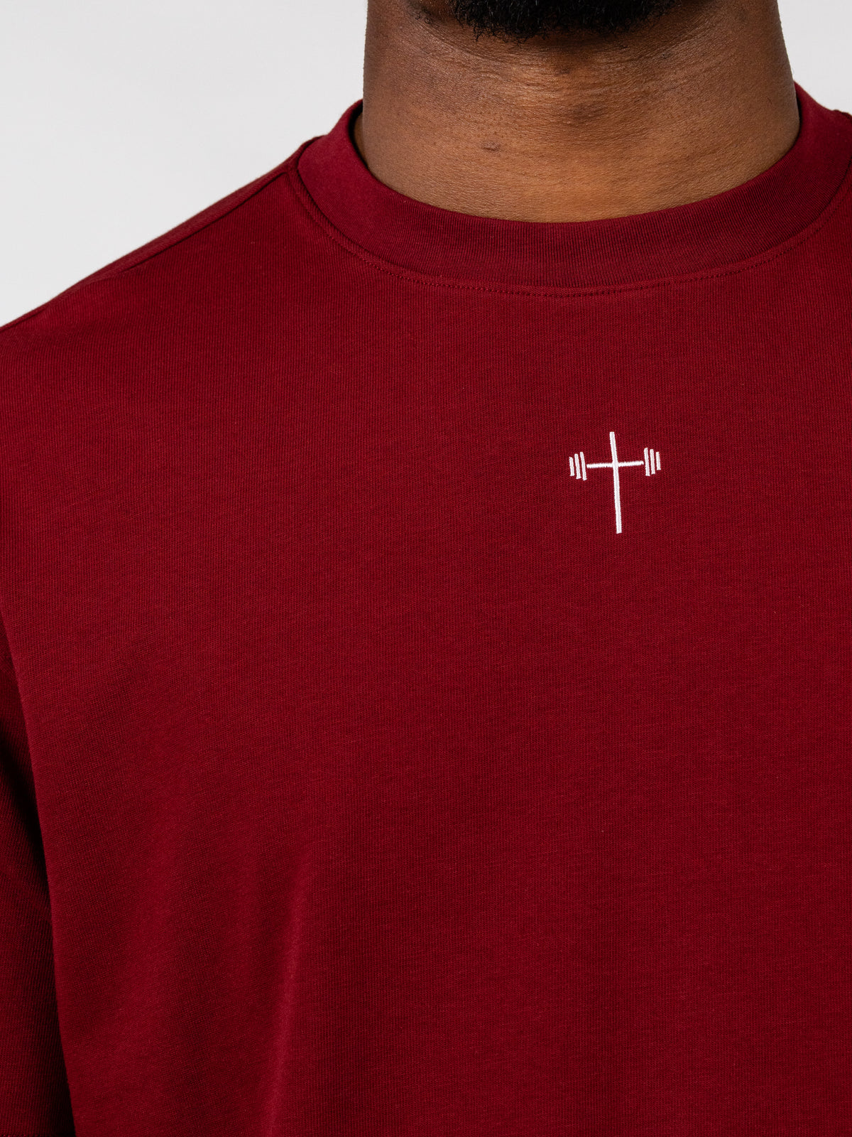 Sacred Heart Premium Oversized Tee in deep red with a small white cross graphic on the chest shown in close-up for Christian apparel lovers