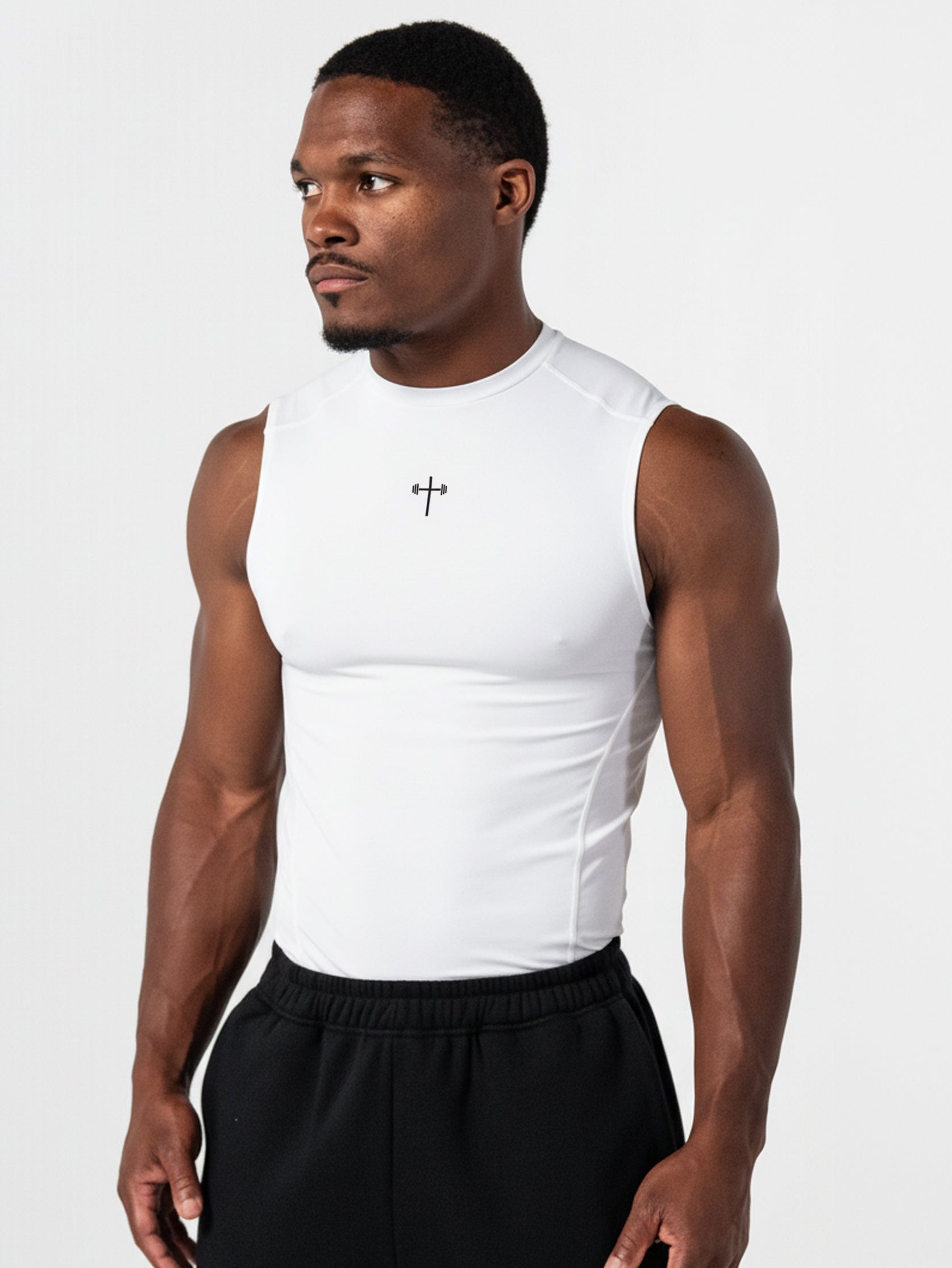 Athletic man wearing a white Premium Compression Tank with a subtle cross design on the chest, paired with black athletic pants, showcasing faith-based fitness apparel.